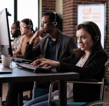 Woman living with disability answering call at customer care service, wheelchair user with physical health condition working at helpline support. Helpdesk operator with chronic pain.