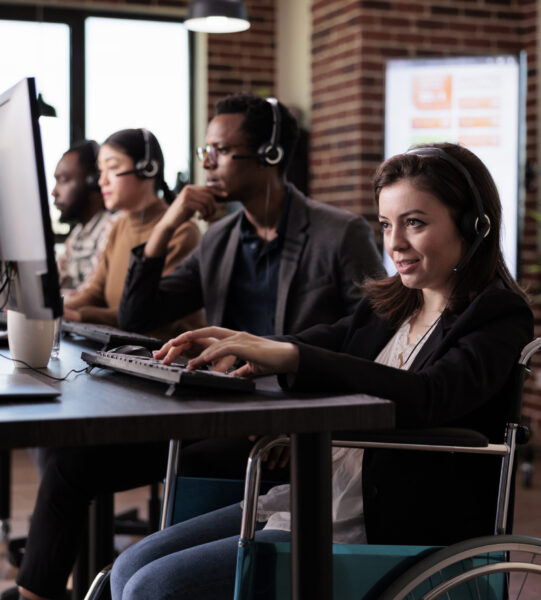 Woman living with disability answering call at customer care service, wheelchair user with physical health condition working at helpline support. Helpdesk operator with chronic pain.