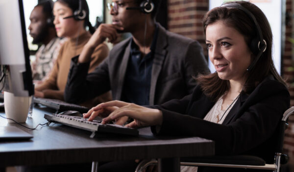 Woman living with disability answering call at customer care service, wheelchair user with physical health condition working at helpline support. Helpdesk operator with chronic pain.